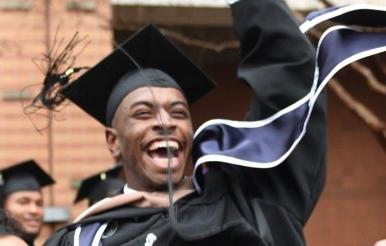 当他被其他毕业生举起来时，毕业生笑了